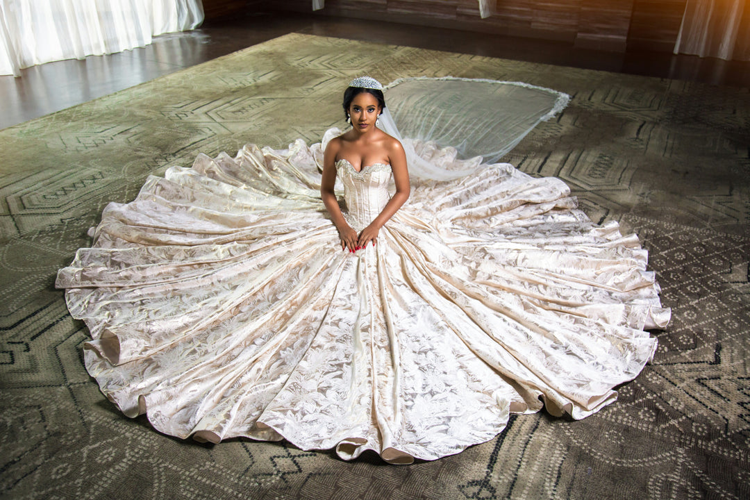 A bride sitting gracefully, displaying the intricate floral brocade texture of a custom handmade wedding ballgown, luxury bridal inspiration by Sewn In The Wood.