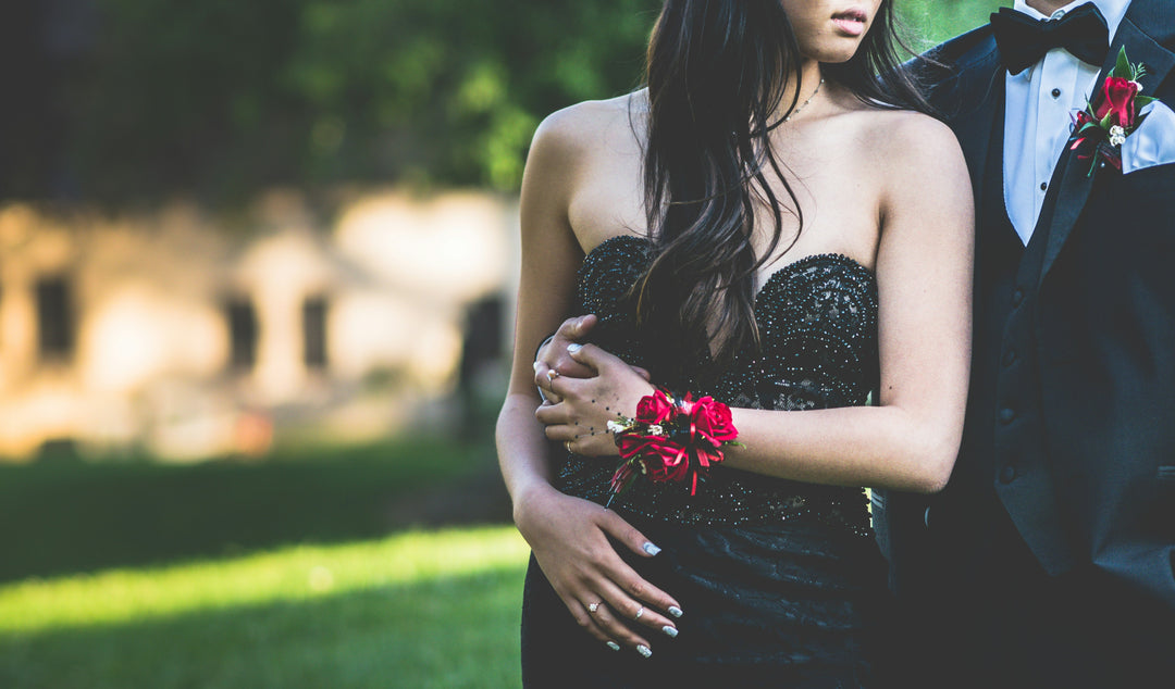 A close-up of a homecoming couple featuring a sharp formal suit and a custom strapless beaded sweetheart dress, luxury homecoming fashion inspiration by Sewn In The Wood.